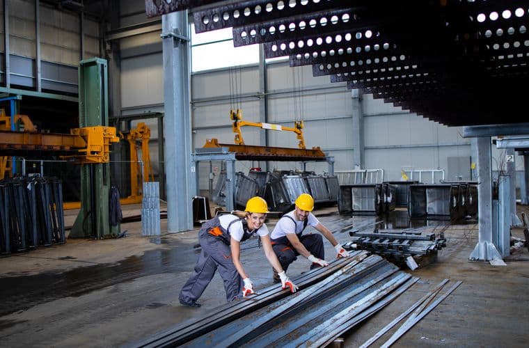 Fabricators moving steel sections across a workshop floor